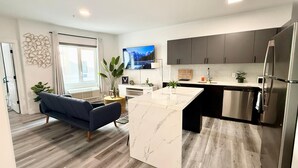 A modern kitchen with a marble island, stainless steel appliances, and a flat-screen TV mounted above the island. - Cozy Chic 1 Bdrm King Suite - mins to NYC, MetLife (Belleville)