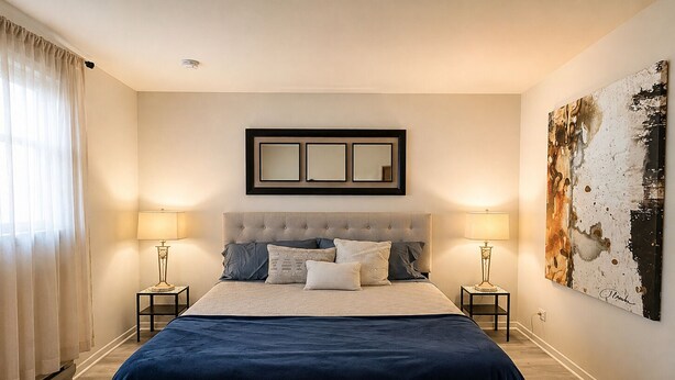 Une chambre à coucher avec un grand lit, deux tables de chevet, une tête de lit et un miroir fixé au mur.