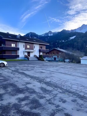 Un hotel de diseño moderno, con un estacionamiento y un paisaje montañoso de fondo.