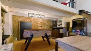 Quarto com mesa de pebolim, espaço de bar e máquina de jogos.