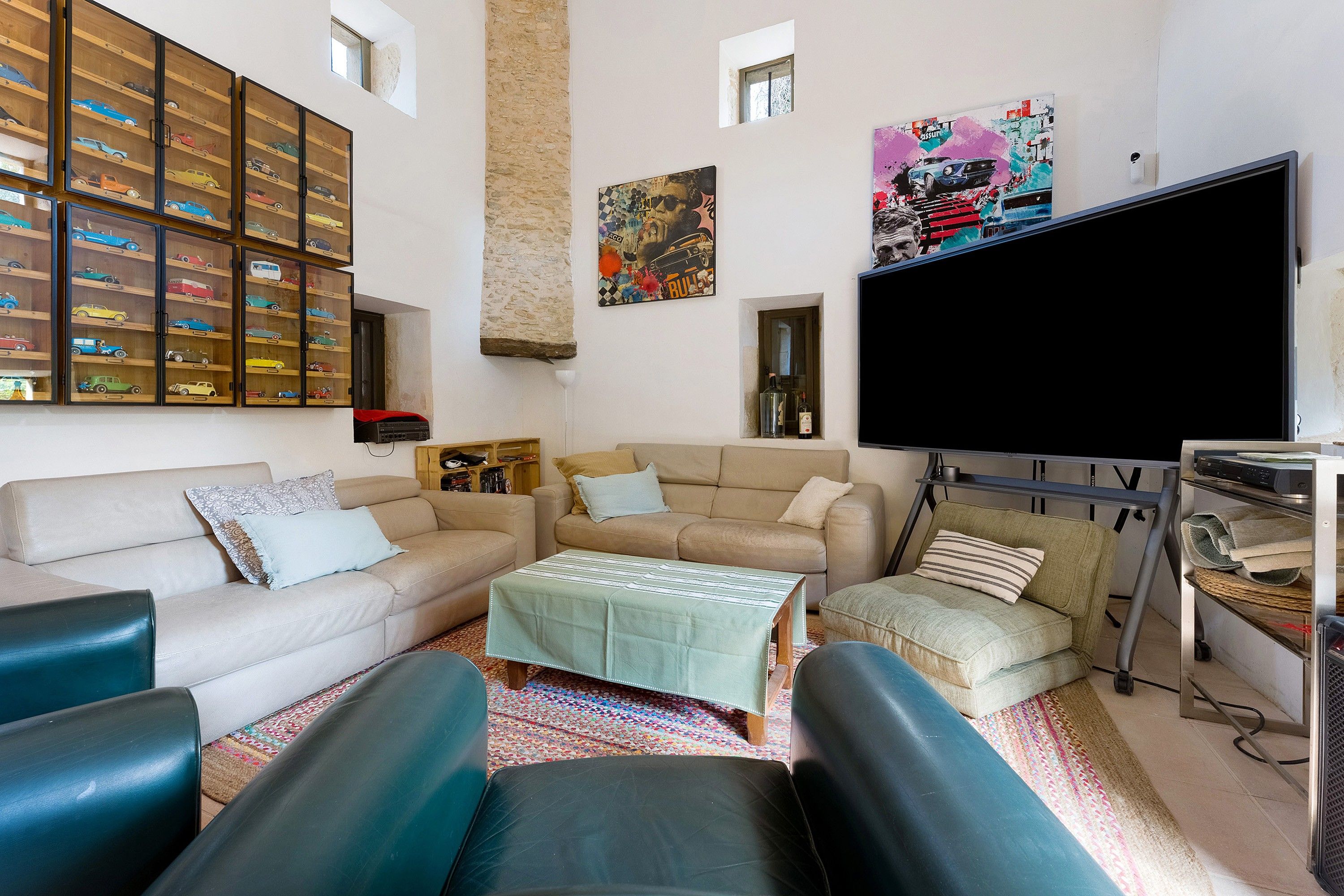 Ein Wohnzimmer mit Sofas, einem Couchtisch, einem Fernseher und einer Vitrine für Autos.
