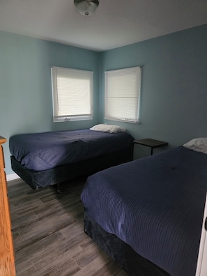 Een kamer met twee bedden, een houten nachtkastje en een klein tafeltje.