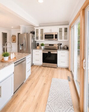 Una cocina moderna con armarios blancos, electrodomésticos de acero inoxidable y piso de madera.