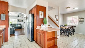 Una cocina moderna con refrigerador empotrado, armarios de madera, una encimera y un comedor con mesa y sillas.