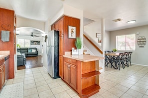 A modern kitchen with a built-in refrigerator, wooden cabinets, a countertop, and a dining area with a table and chairs.