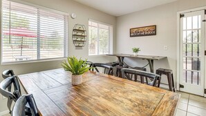 Comedor con mesa de madera, sillas, planta en maceta y estante con plantas.