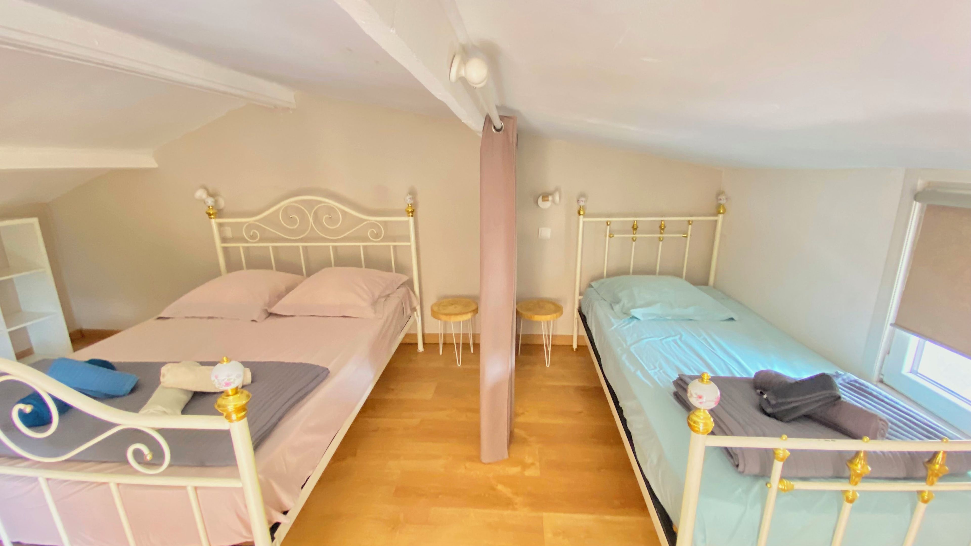 A bedroom with two single beds, a small table, and a window.