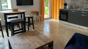 Una cocina moderna con televisor de pantalla plana, un comedor con mobiliario de madera y vistas a la vegetación.