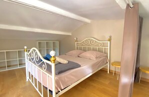 A single bed with a white metal frame and a headboard with decorative elements, a bedside table, and a small stool. - Charming New Cottage with Pool near Uzès – Sleeps 2–3 (Saint-Siffret)