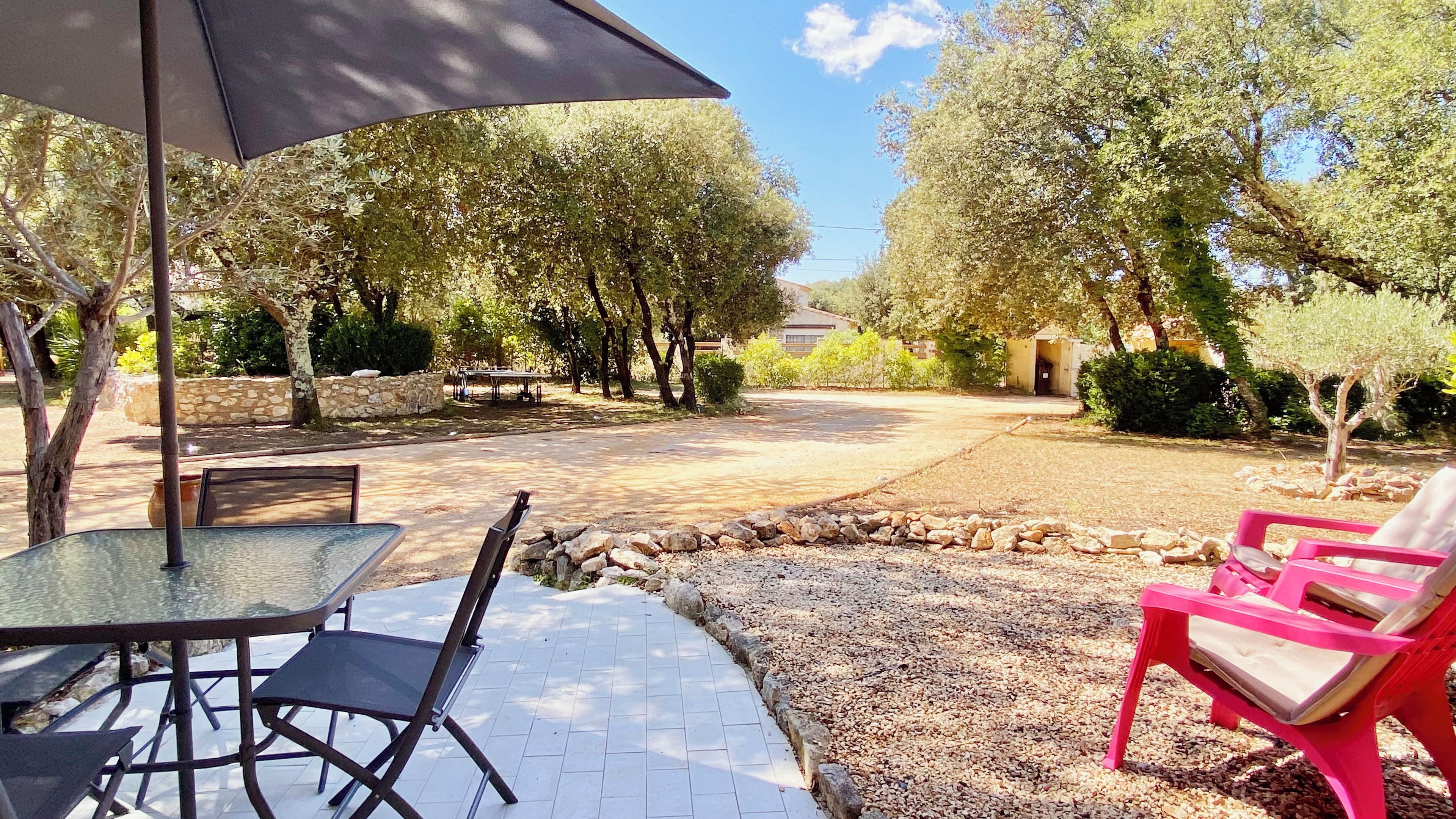 An outdoor patio with a table and chairs, a stone wall, and a gravel area.
