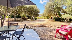 Eine Terrasse im Freien mit Tisch und Stühlen, einer Steinmauer und einem Bereich mit Kies.