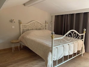 Ein Einzelbett mit weißem Metallgestell, ein kleiner Nachttisch und eine Wandleuchte.
