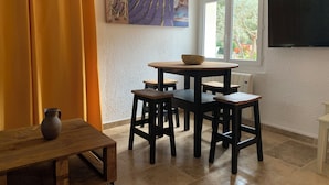 Un comedor con una mesa redonda, cuatro sillas, una mesita con una jarrón y un televisor montado en la pared.