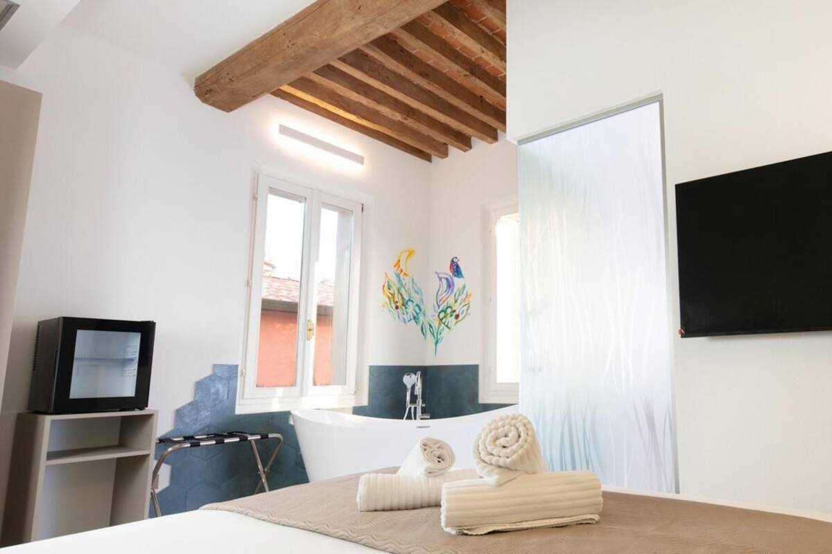 Habitación de hotel con cama, televisor, bañera y televisor montado en la pared.