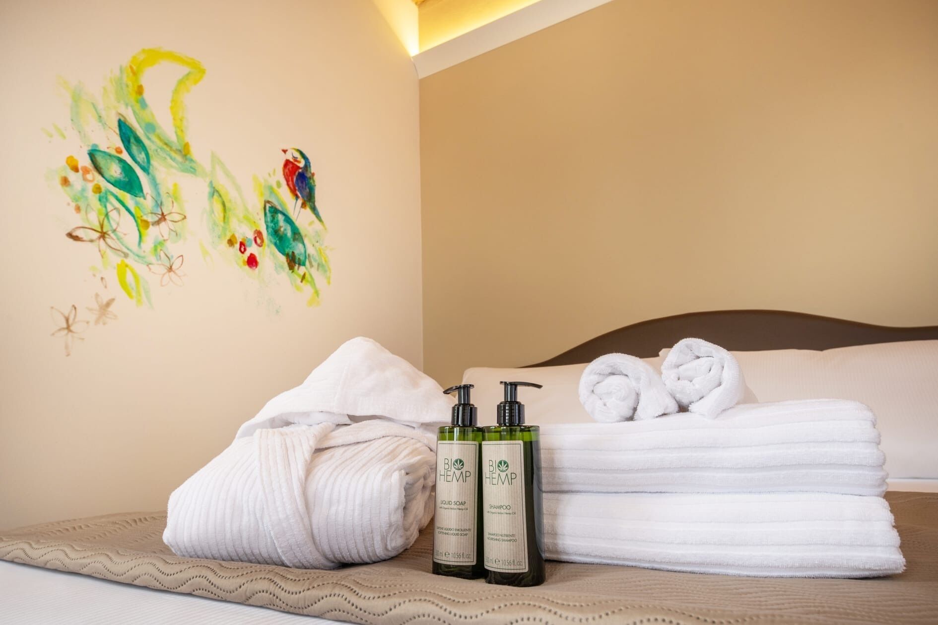 A hotel room with a bed, towels, and two bottles of hemp-based products.