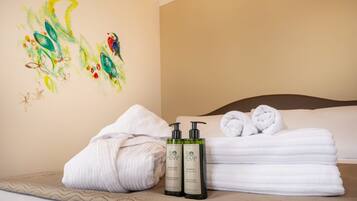 A hotel room with a bed, towels, and two bottles of hemp-based products.