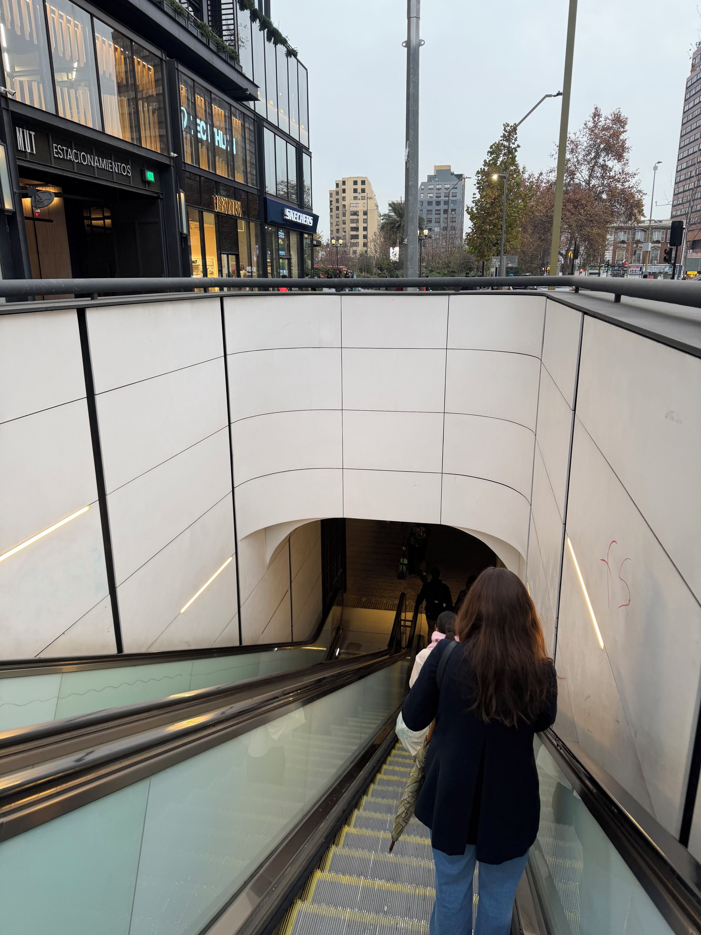 Een roltrap in een openbare ruimte, met een modern architectonisch ontwerp, omgeven door glazen panelen en metalen leuningen.