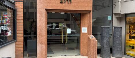A building entrance with a brick facade, a glass door, and a metal number sign.