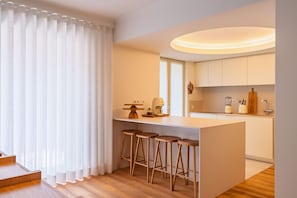 A modern kitchen with a central island, bar stools, and a window with sheer curtains. - Z - Market Residence 3D (Porto)