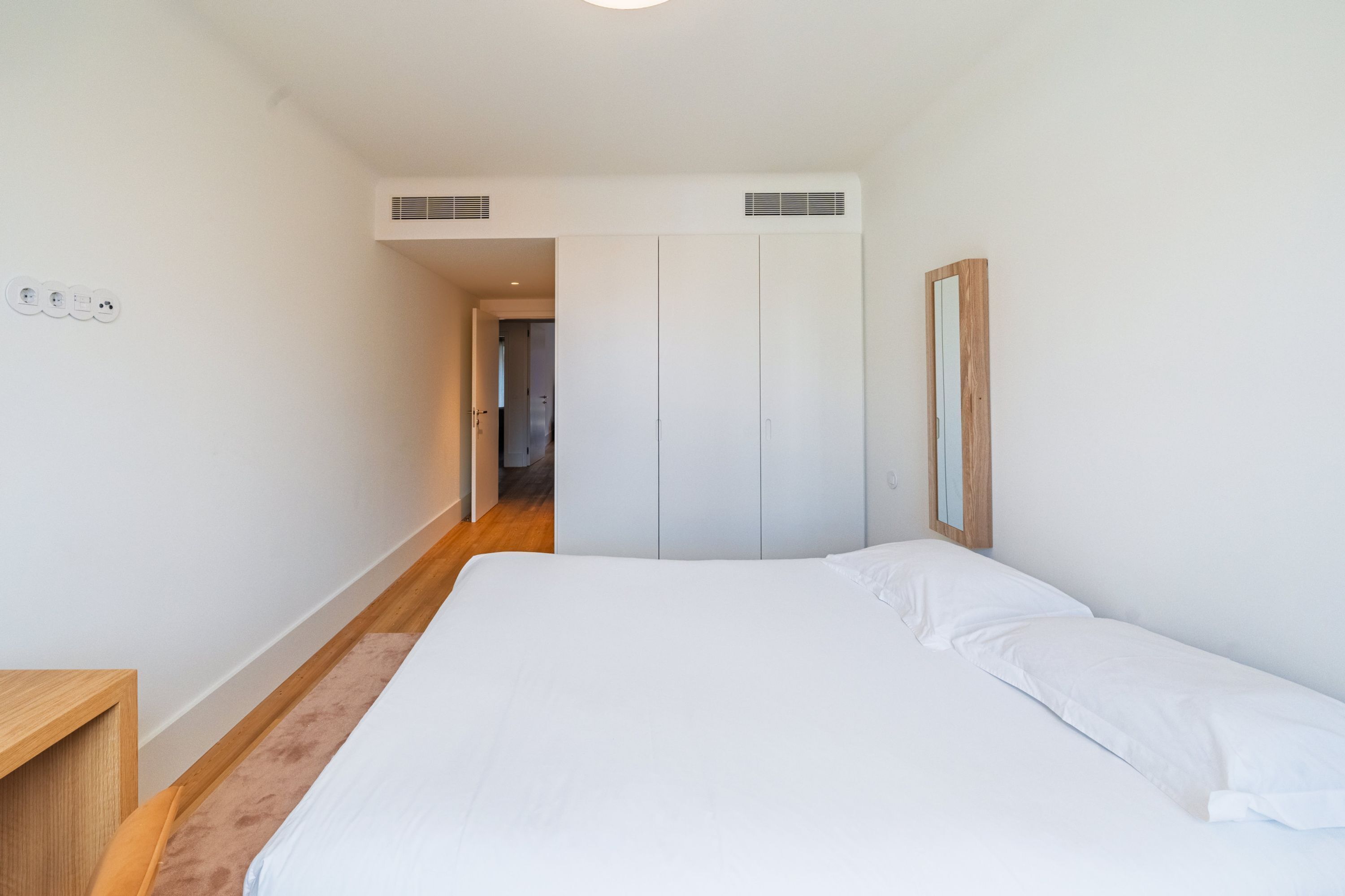 Une chambre à coucher avec un lit, une armoire et une table de chevet en bois.