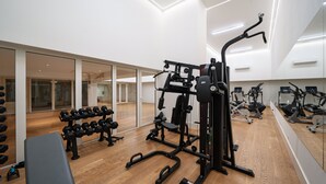 Ein Fitnessraum mit Trainingsgeräten, einer Bank und Kurzhanteln.