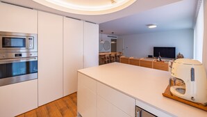 Eine moderne Küche mit integrierten Geräten, einer Kochinsel und einem Essbereich mit Fernseher.