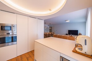 A modern kitchen with built-in appliances, a central island, and a dining area with a TV. - Z - Market Residence 3D (Porto)