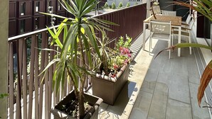 A balcony with potted plants, a wooden table, and chairs. - Z - Market Residence 1D (Porto)