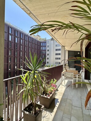 A balcony with potted plants, a wooden table, and chairs. - Z - Market Residence 1D (Porto)