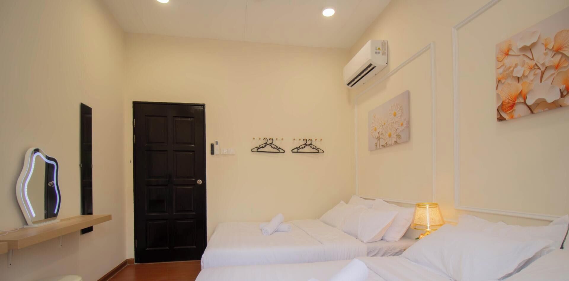 Une chambre d’hôtel comprenant un lit, une table de chevet, une lampe, un climatiseur fixé au mur et une porte.