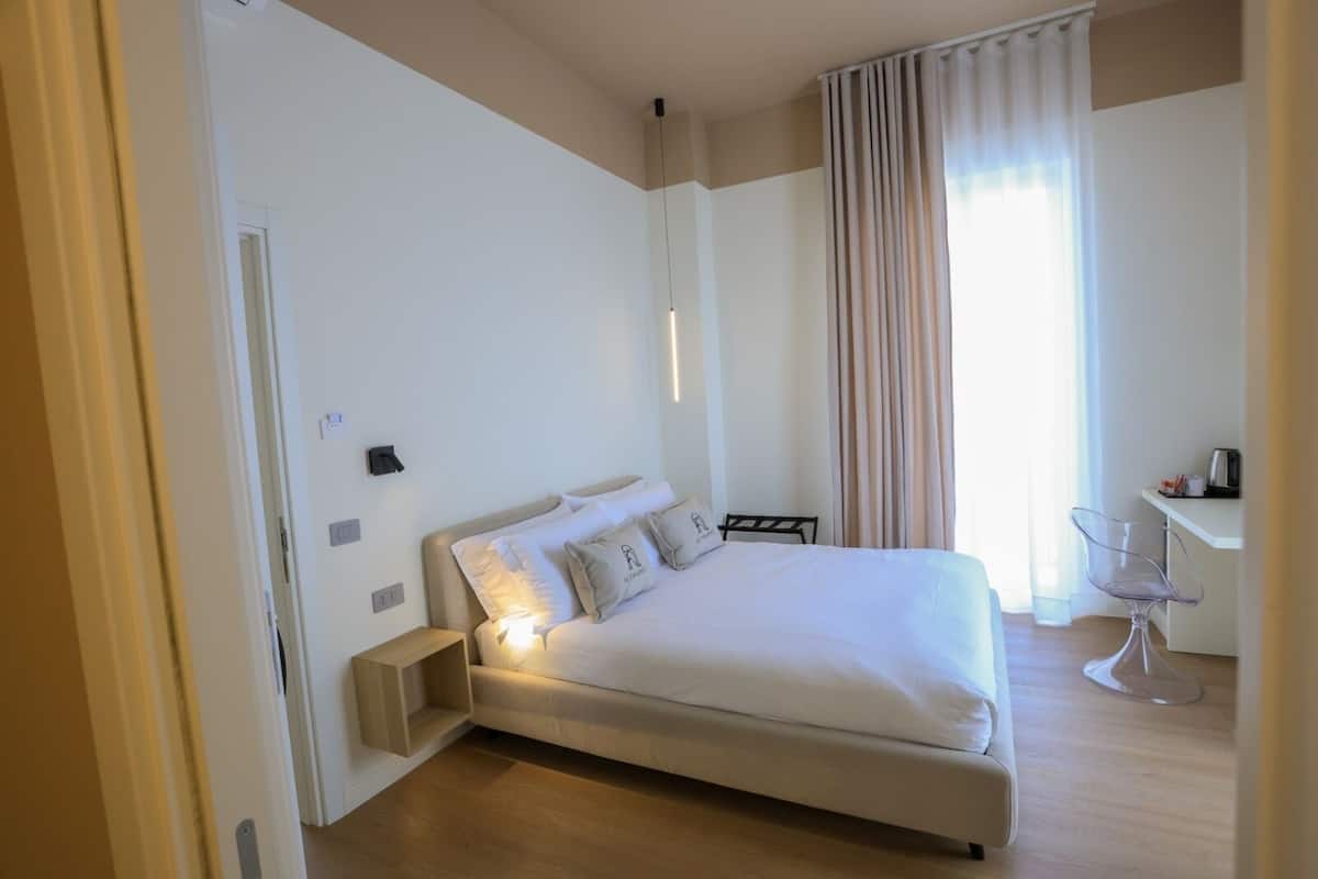 Un dormitorio moderno con cama, mesita de noche y escritorio con silla.