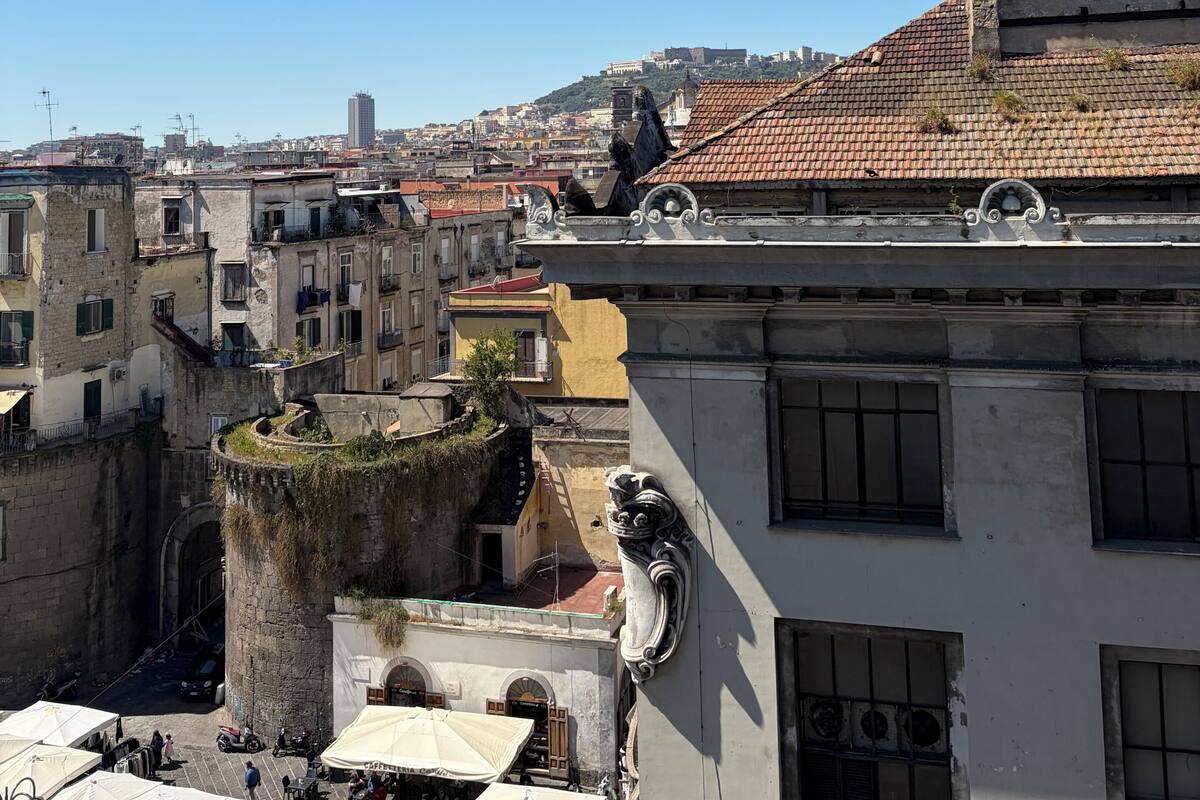 Un paisaje urbano con edificios históricos, cielo despejado y vistas de la ciudad al fondo.