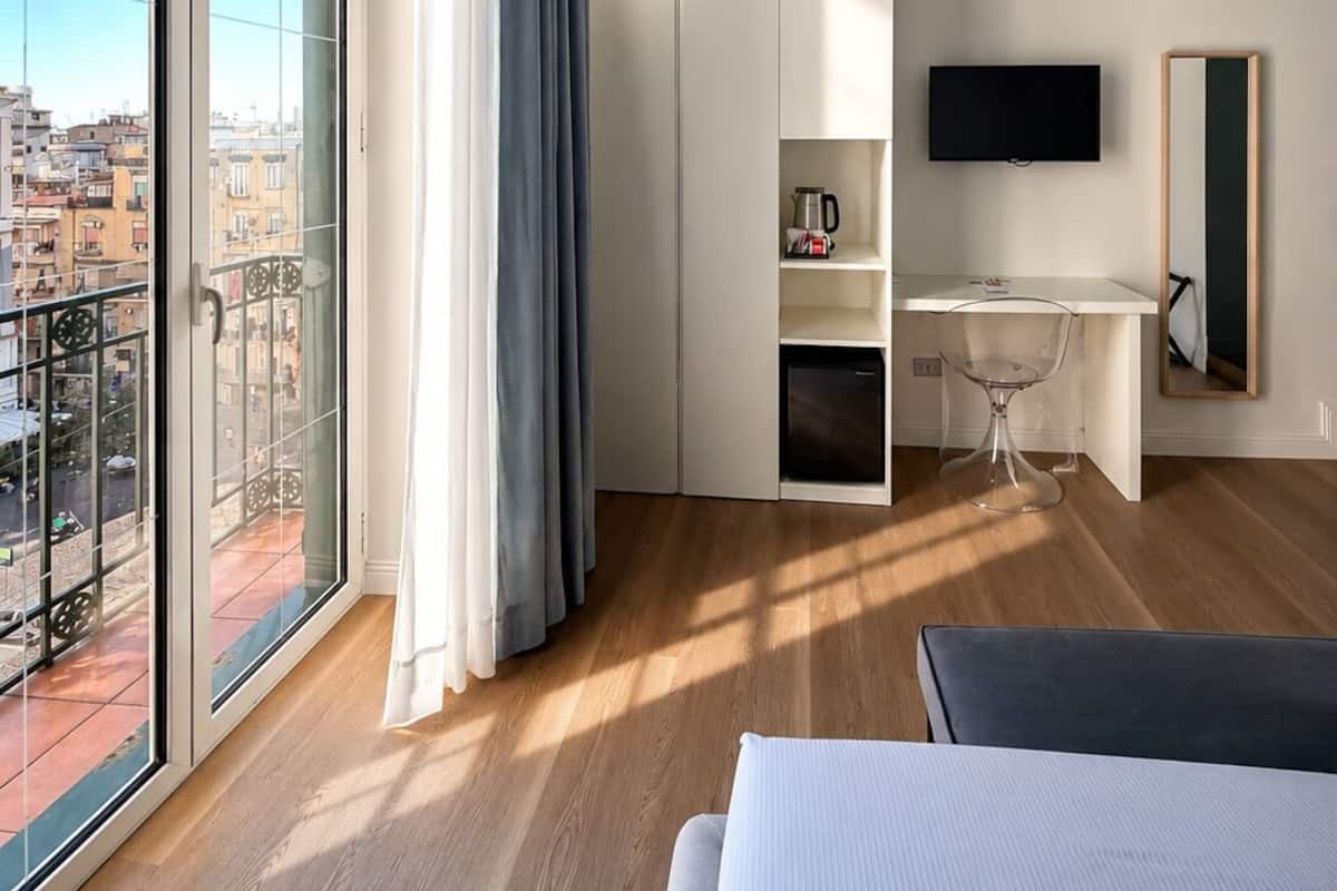 Una habitación de hotel moderna con balcón, escritorio, cama y televisor.