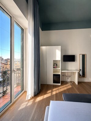 A modern hotel room with a balcony, a desk, a bed, and a TV. - Altanapoli Rooms & Suites (Napoli)