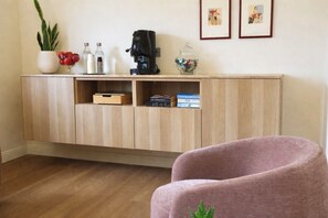 A wooden cabinet with a coffee maker, bottles, and a plant on top. - Altanapoli Rooms & Suites (Napoli)
