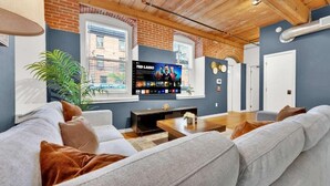 Ein modernes Wohnzimmer mit großem Flachbildfernseher, einer Couch, einem Couchtisch und einer Topfpflanze.
