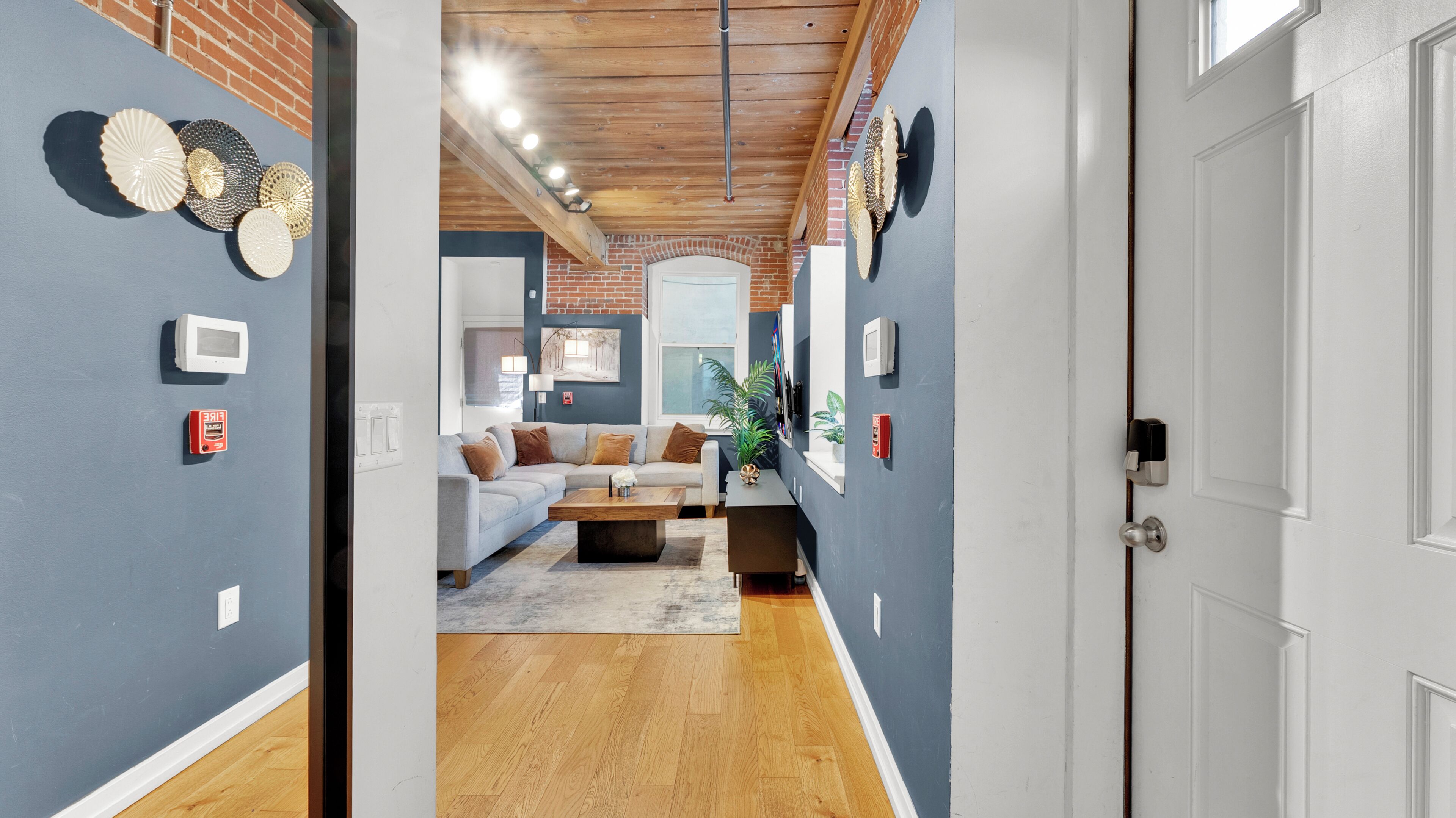 A hallway leading to a living room with a sofa, coffee table, and decorative wall art.