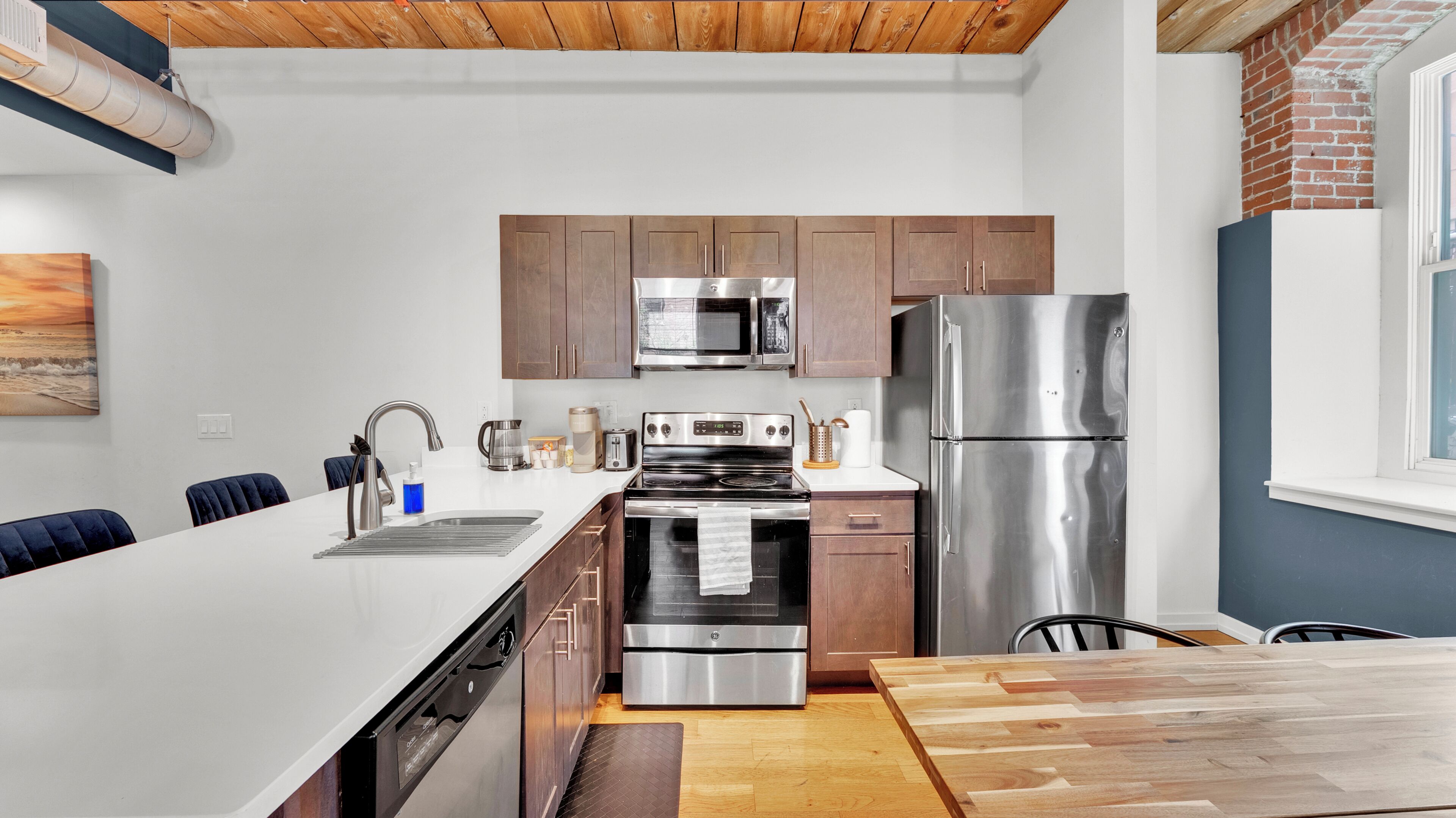 A modern kitchen with stainless steel appliances, wooden cabinets, and a large island.