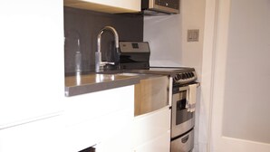 A compact kitchen with a stainless steel range hood, a built-in oven, and a dishwasher. - New York Style Stay near Central Park (New York)
