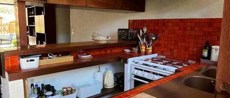 A kitchen with wooden cabinets, a red-tiled backsplash, a wooden countertop, and a built-in stove.