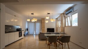 Una cocina moderna con armarios blancos, horno integrado y microondas. Cuenta con un comedor con mesa de vidrio y sillas.