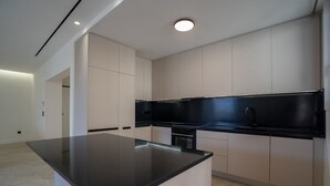 Una cocina moderna con encimera negra, armarios blancos e iluminación empotrada en el techo.