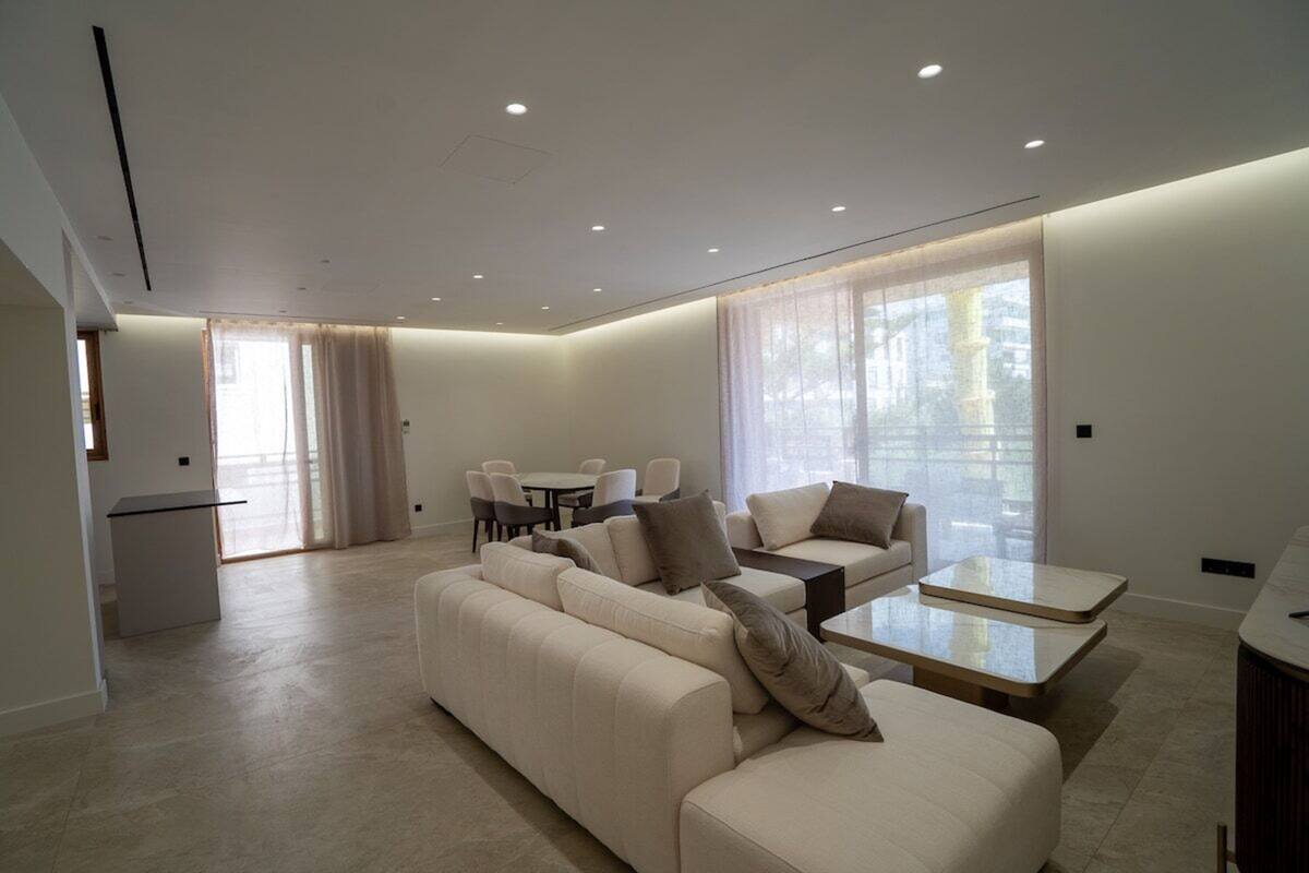 A modern living room with a sofa, coffee table, and dining area.