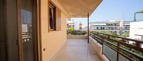 A balcony with a view of other buildings, a glass door, and a railing.