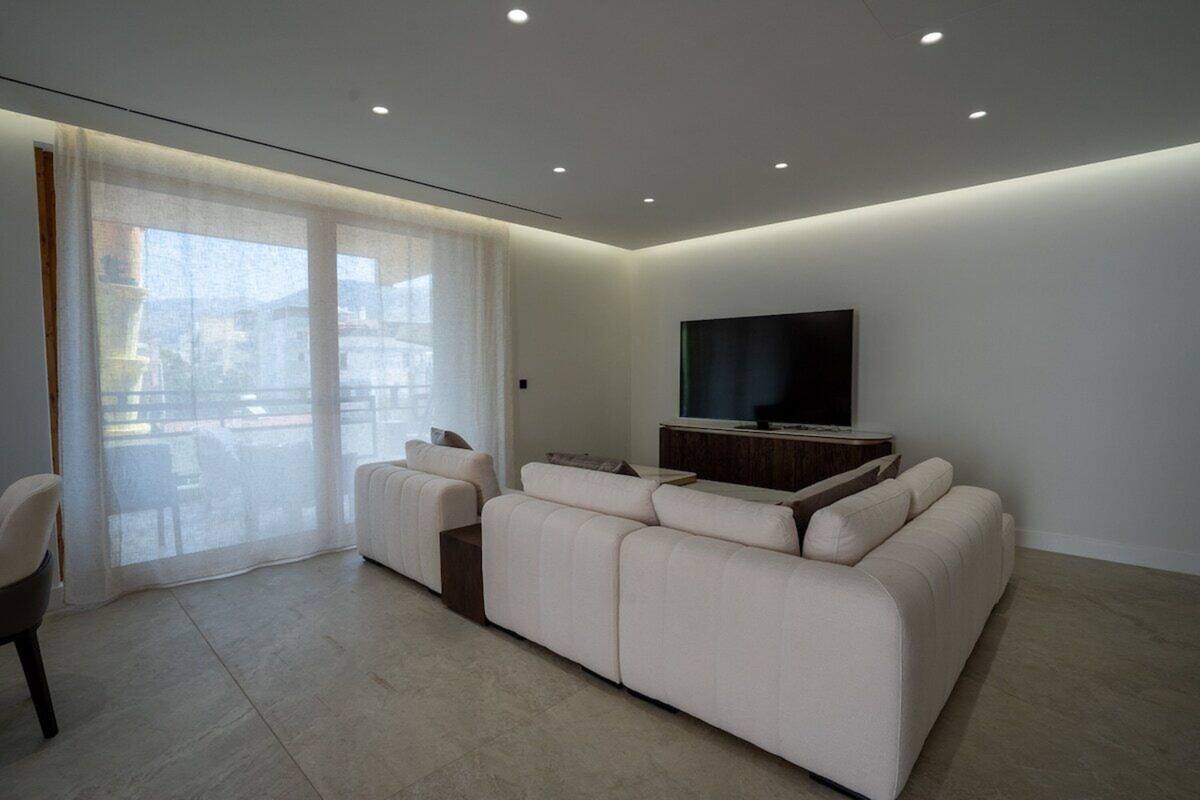 A modern living room with a sofa, a TV, and a sliding glass door.