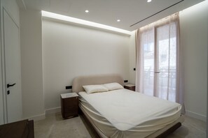 Une chambre à coucher avec un lit, des tables de chevet, une commode et une fenêtre avec des rideaux.
