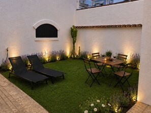 A patio with a table and chairs, a small window, and a cactus. - La Piavera (Apartment with Private Garden) (La Laguna)