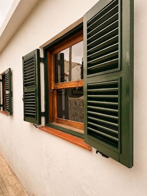 Ein Gebäude mit einem Fenster, ausgestattet mit grünen Fensterläden und einem Holzrahmen.