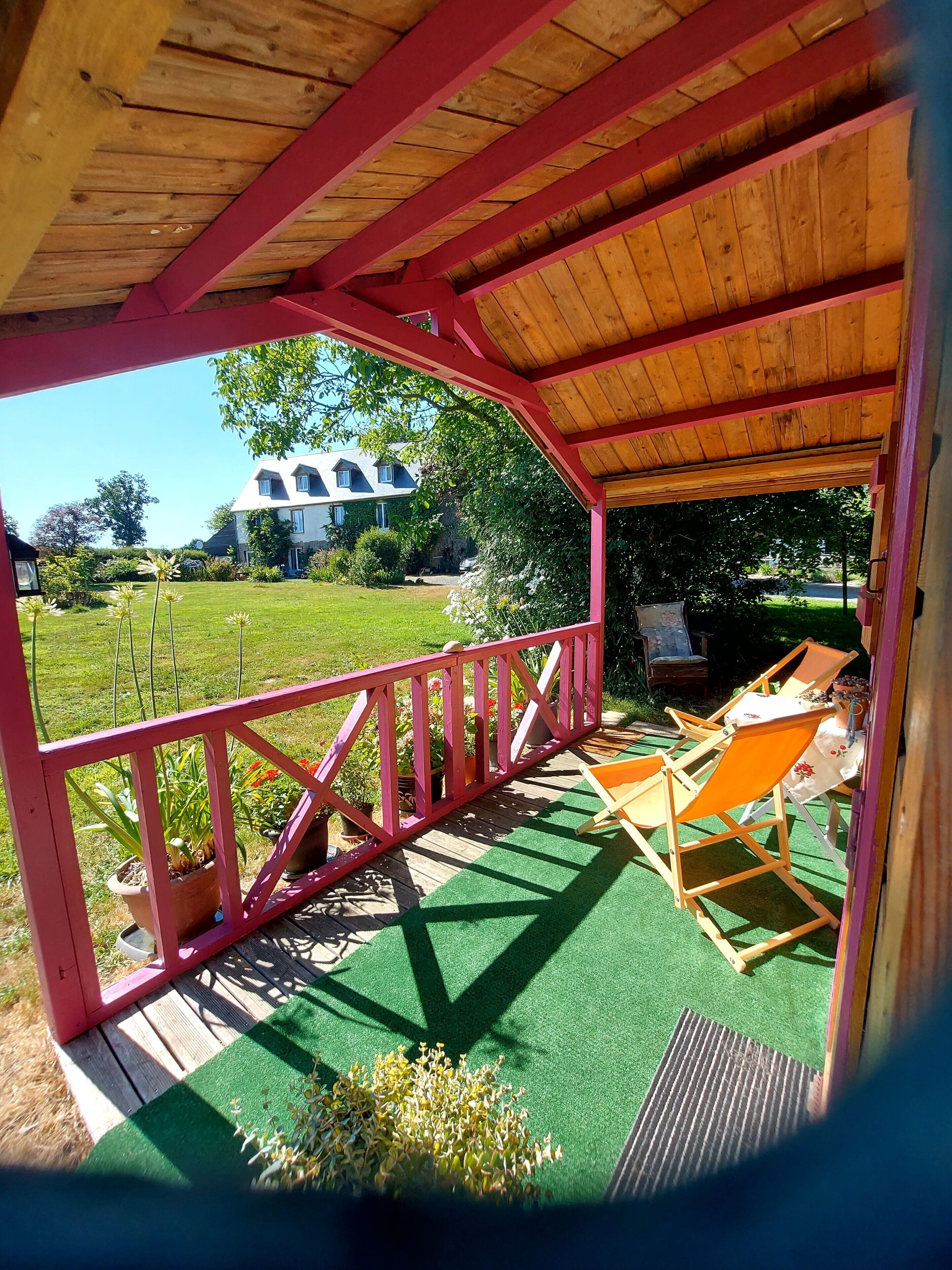 A covered outdoor area with a wooden ceiling, a red railing, and a green artificial turf.