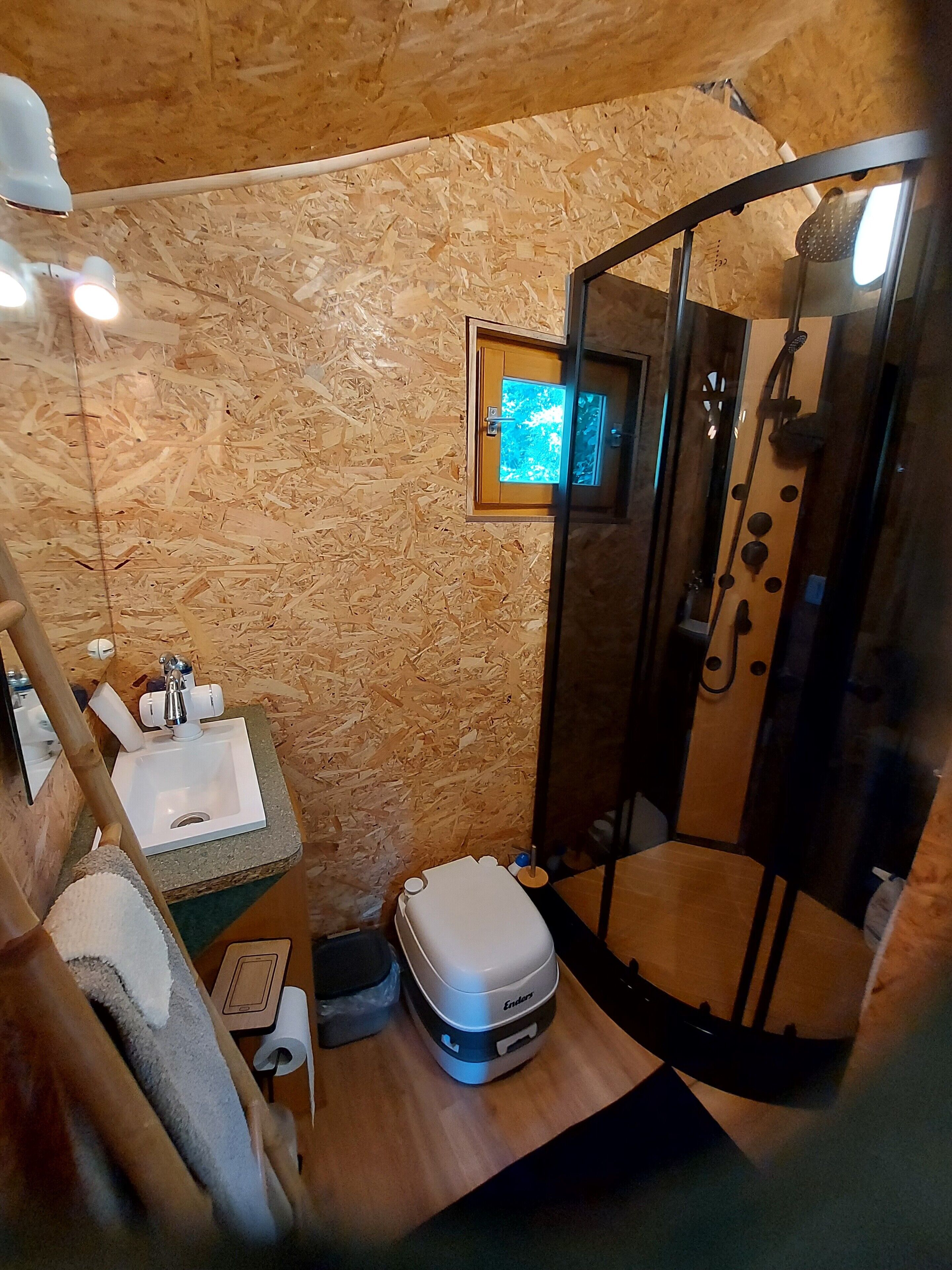 Et lille badeværelse med vask, toilet og bruseniche.